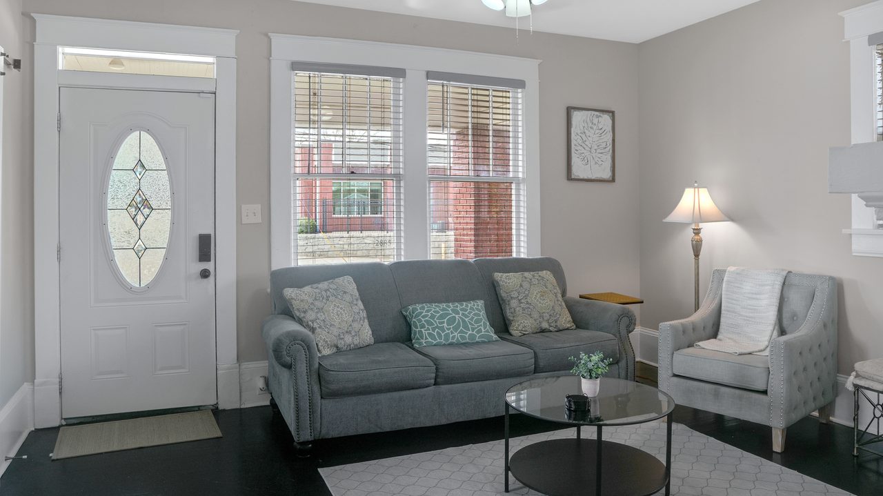 Living room with a grey sofa and front door in a short term rental