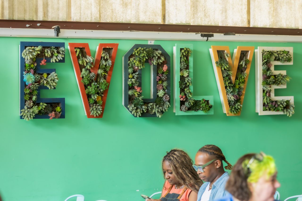 Guests seated beneath a living wall that spells Evolve at FreshBooks Small Talk ATL