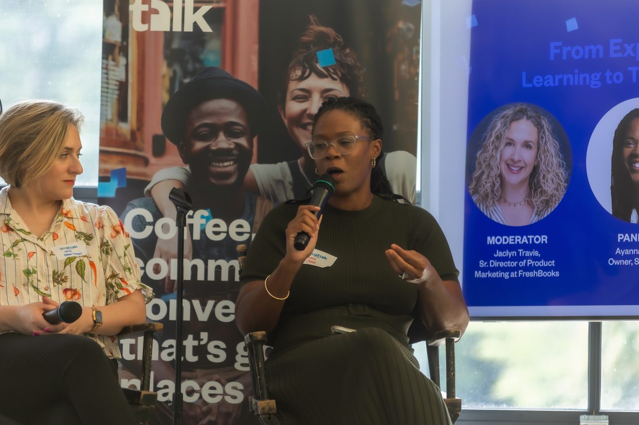 Panel of four women seated on stage in front of Small Talk branding