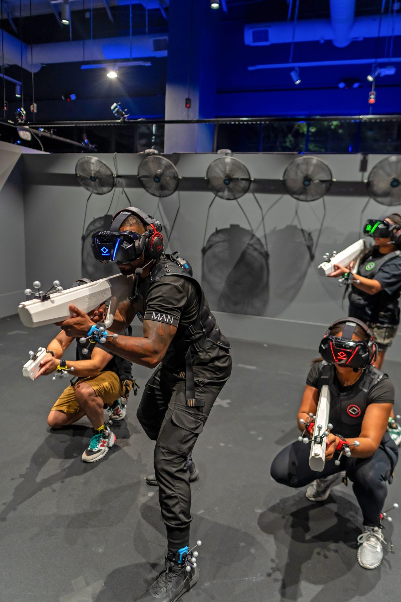 Tournament players aiming VR blasters inside the Sandbox VR arena