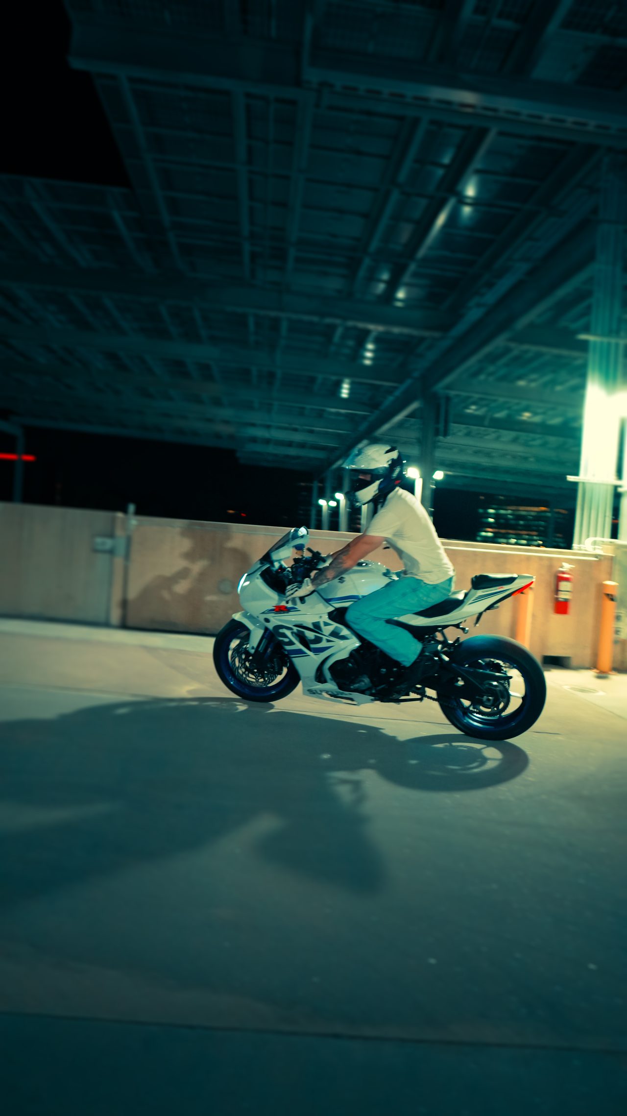 Rider beside a sport bike under deck lights