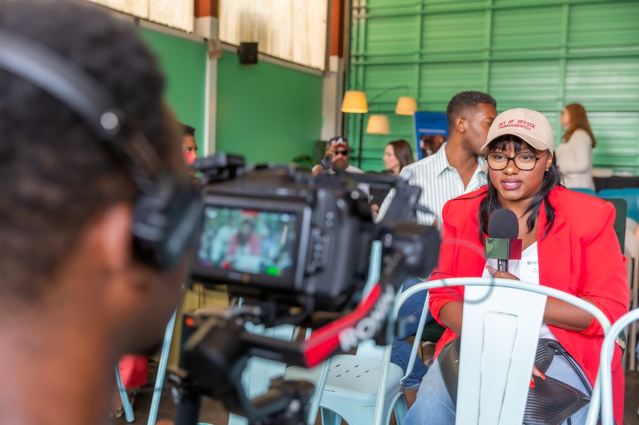 Camera operator with headphones framing a shot at a panel